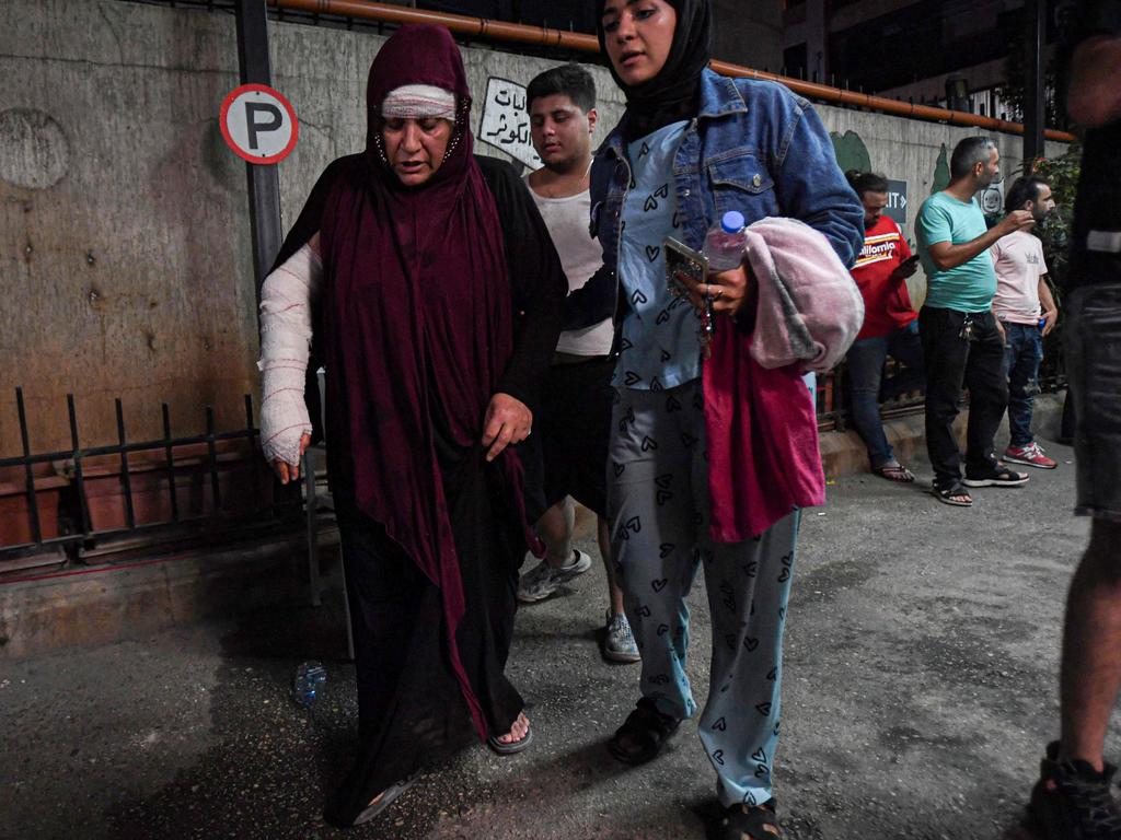 A woman injured in an Israeli military strike on a building in Beirut's southern suburbs is escorted as she leaves the Brahman hospital. Picture: AFP