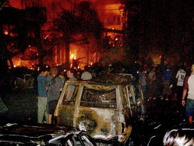 People look at the damage after explosions rocked two nightclubs in Kuta Beach Bali Oct 12, 2002. At least 100 people were killed in the car bomb outside Paddy's Pub & Sari Club. REUTERS picRakadeni/Radar /Bali /Newspapers crime o/seas Indonesia terrorism bombings scene fires flames wreckage