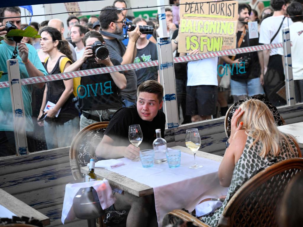 Diners cower as anti-tourism protesters target them with water guns at city-wide protests in Barcelona. Picture: AFP