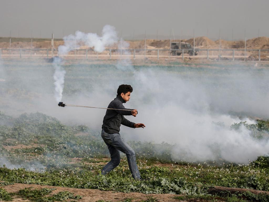 A Palestinian protester uses a slingshot to throw back a tear gas canister at Israeli forces following a demonstration near the fence along the border with Israel, east of Gaza City. Picture: AFP