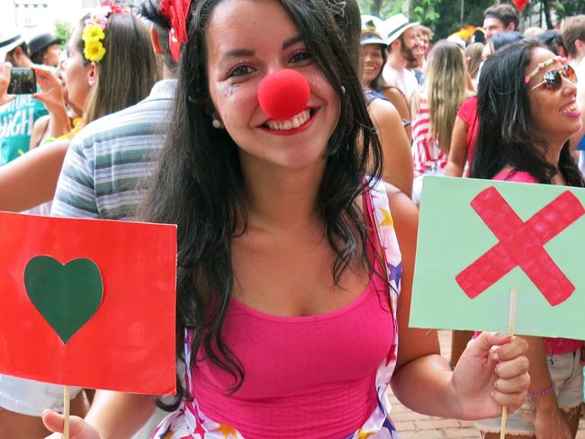 Luiza Rocha, a 22-year-old university student, holds up placards with symbols used on the hookup app Tinder at the Tinder-themed debut street party "Match Comigo" in Rio de Janeiro, Brazil, Monday, Feb. 16, 2015. The heart symbol on the app is tapped to show that you like a suggested match and the X symbol is used decline the match. The brainchild of a 28-year-old publicist who says he’s “met lots of nice people on Tinder,” the “Match Comigo” street party aims to introduce a high-tech edge to the Carnival’s multifold, fleeting romances. (AP Photo/Jenny Barchfield)