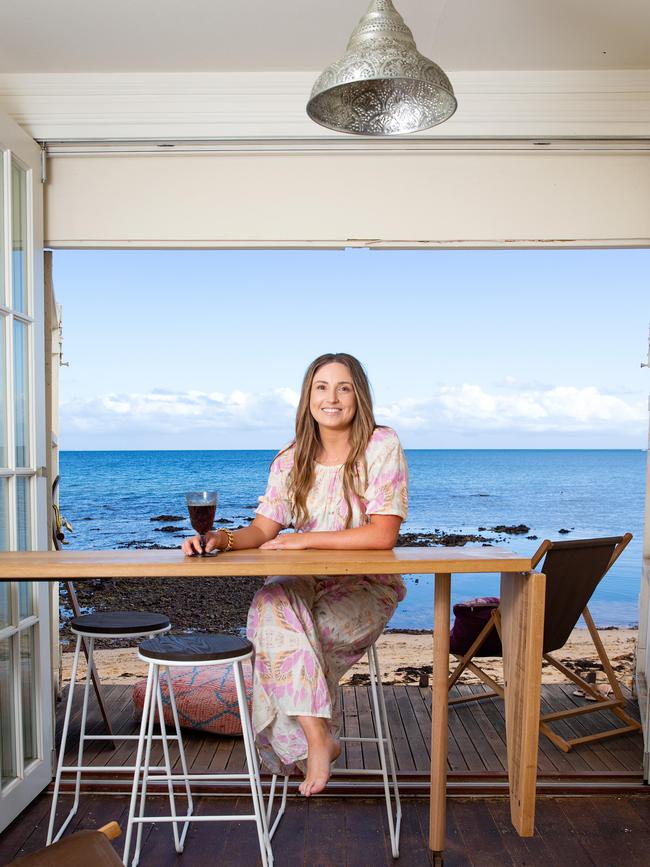 Alicia Morgan at the Mt Eliza beach box she and husband Des Bankier formerly owned. The box has a bar that swivels to face the water and bi-fold doors concealed by pop art. Picture: Sarah Matray