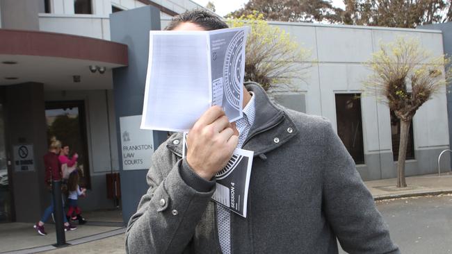 Ryan Wells covered his face as he leaves the Frankston Magistrate Court this morning facing charges over an unprovoked hit to a man walking past him on a street. Picture: David Crosling