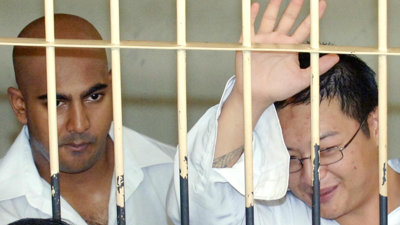 Andrew Chan (right) waves to wellwishers as Myuran Sukumaran (left) looks on from behind the bars of a court cell before their trial in Denpasar in February 2006. Picture: AFP Photo/Jewel Samad