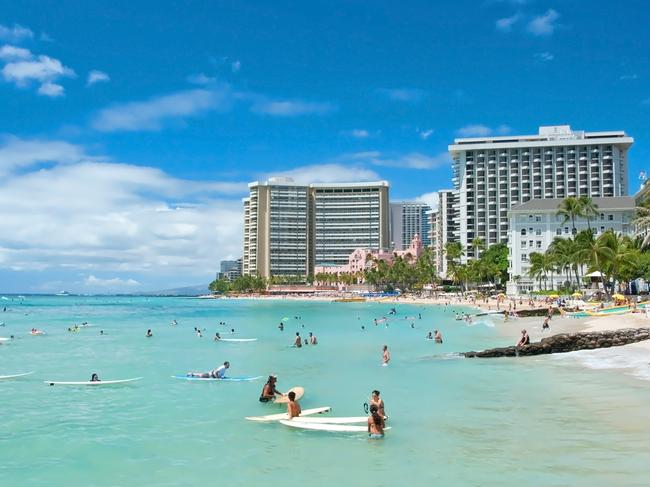 ESCAPE: Learn to surf in WaikikiOahu, Hawaii - September 19, 2011 - Tourist sunbathing and surfing on Waikiki beach in Oahu. Waikiki beach is beachfront neighborhood of Honolulu, best known for white sand and surfing.