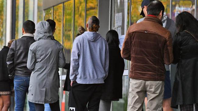 People queue up outside a Centrelink office in Melbourne on April 20, 2020, which delivers a range of government payments and services for retirees, the unemployed, families, carers and parents amongst others. - A report from the Grattan Institute predicts between 14 and 26 per cent of Australian workers could be out of work as a direct result of the coronavirus shutdown, and the crisis will have an enduring impact on jobs and the economy for years to come. (Photo by William WEST / AFP)