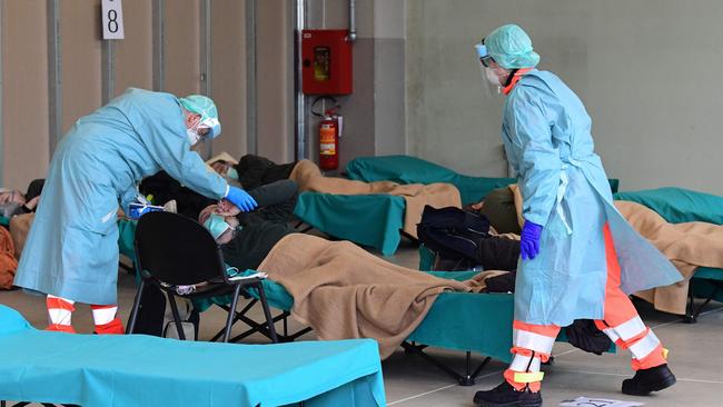 Medical staff at an emergency outdoor hospital unit in Italy’s coronavirus epicentre tend to a patient. Picture: Miguel Medina.