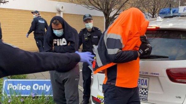 The two men are escorted to a police vehicle and will be driven back to the Victorian border by SA Police. Picture: Nine News Adelaide