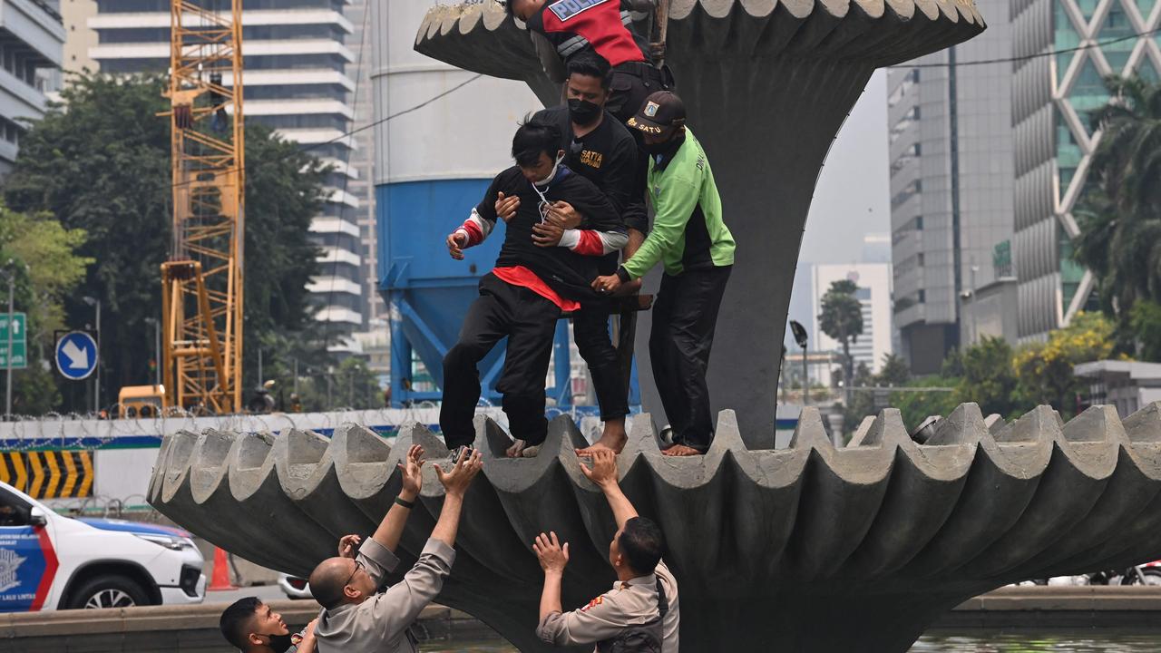 Police arrest a protester who climbed a fountain near the presidential palace during a protest by students. Picture: ADEK BERRY / AFP