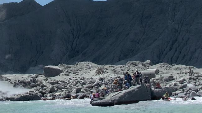 Tourists wait to leave White Island after the eruption of the volcano, which blasted ash and scalding steam killing multiple people. Picture: Michael Schade via AP