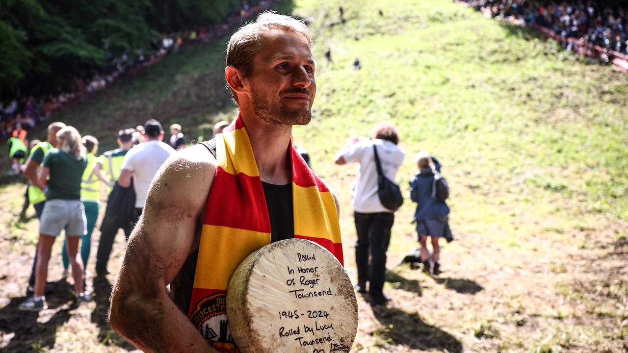 Aussie man Dylan Twiss celebrates after winning race two in the annual Cooper’s Hill cheese rolling competition. Picture: Henry Nicholls/AFP