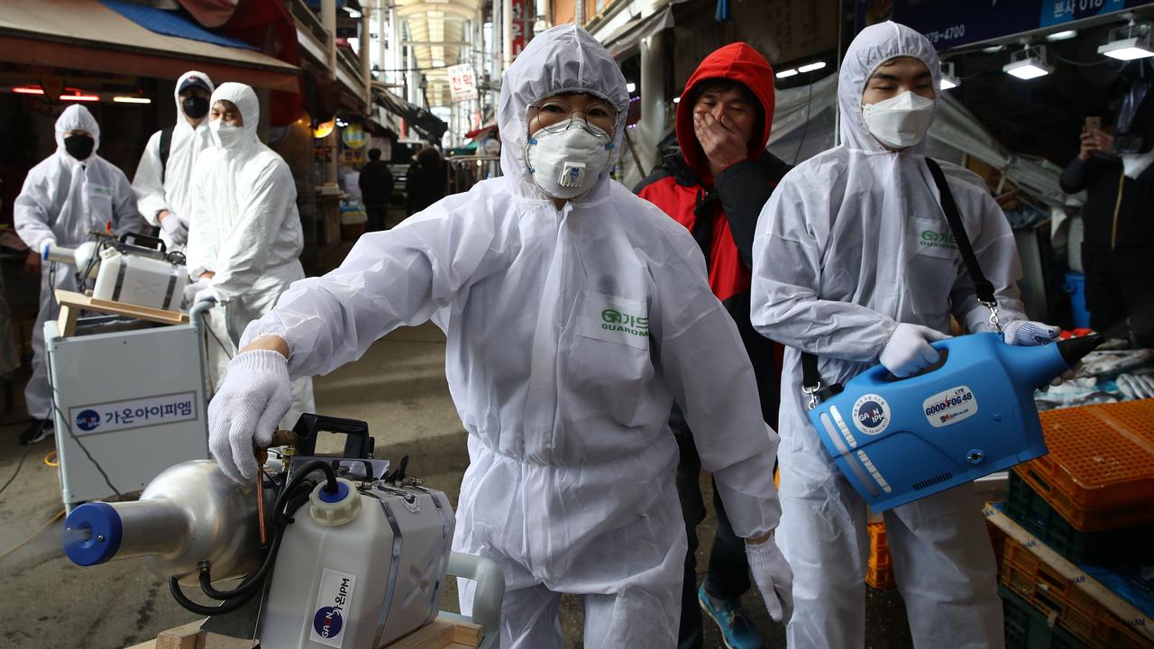 Disinfection professionals wearing protective gear spray antiseptic solution against the coronavirus (COVID-19) at a traditional market. Picture: Getty Images