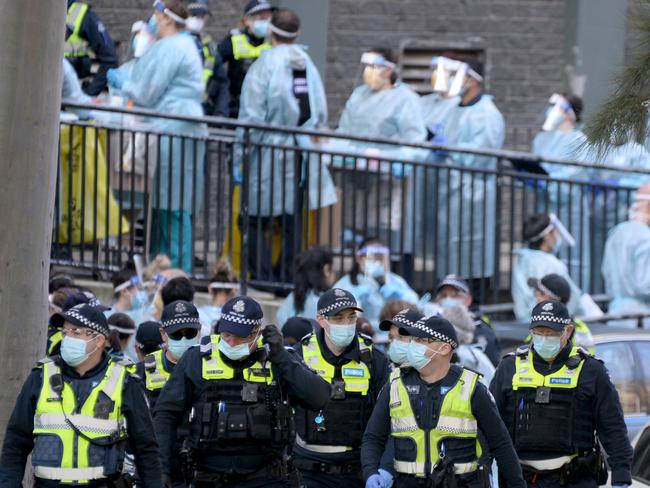 Police and healthcare workers at the locked down North Melbourne public housing estate. Picture: Andrew Henshaw