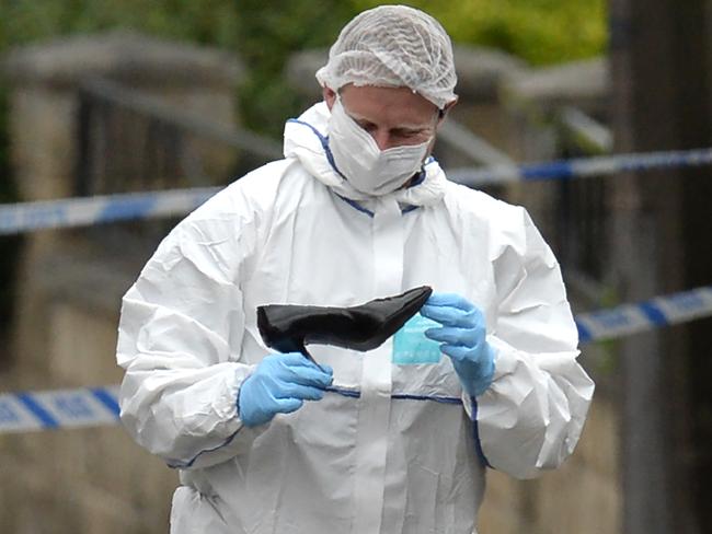 A police forensic officer picks up a shoe from the crime scene on the pavement outside the library in Birstall, northern England, where Labour MP Jo Cox was shot on June 16. Picture: OLI SCARFF