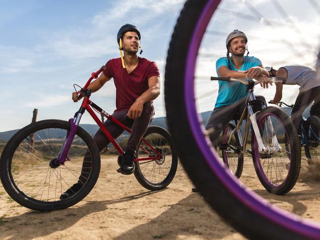 Young male extreme sportsmen resting on their bikes after exercising on dirt road in nature.