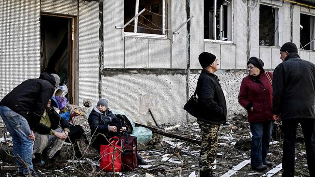 People stand outside a destroyed building in Chuguiv after bombings on February 24, 2022. Picture: Aris Messinis / AFP