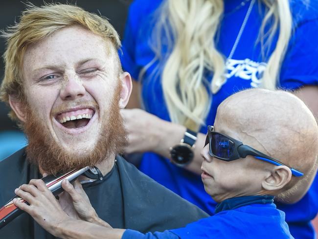 Glenelg footballer Josh Scott his getting his head shaved at a charity day to raise money for 7yo Enzo Cornejo (pictured) with clippers. NB. ENZO PUT THE HAIR ON HIS OWN HEAD12th April 2019. Pic.AAP/ Roy VanDerVegt