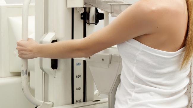 A young woman having taking a mammogram, looking at the camera