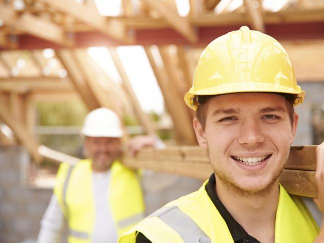 Builder and apprentice carrying wood on construction site.Source: iStock / Getty Images