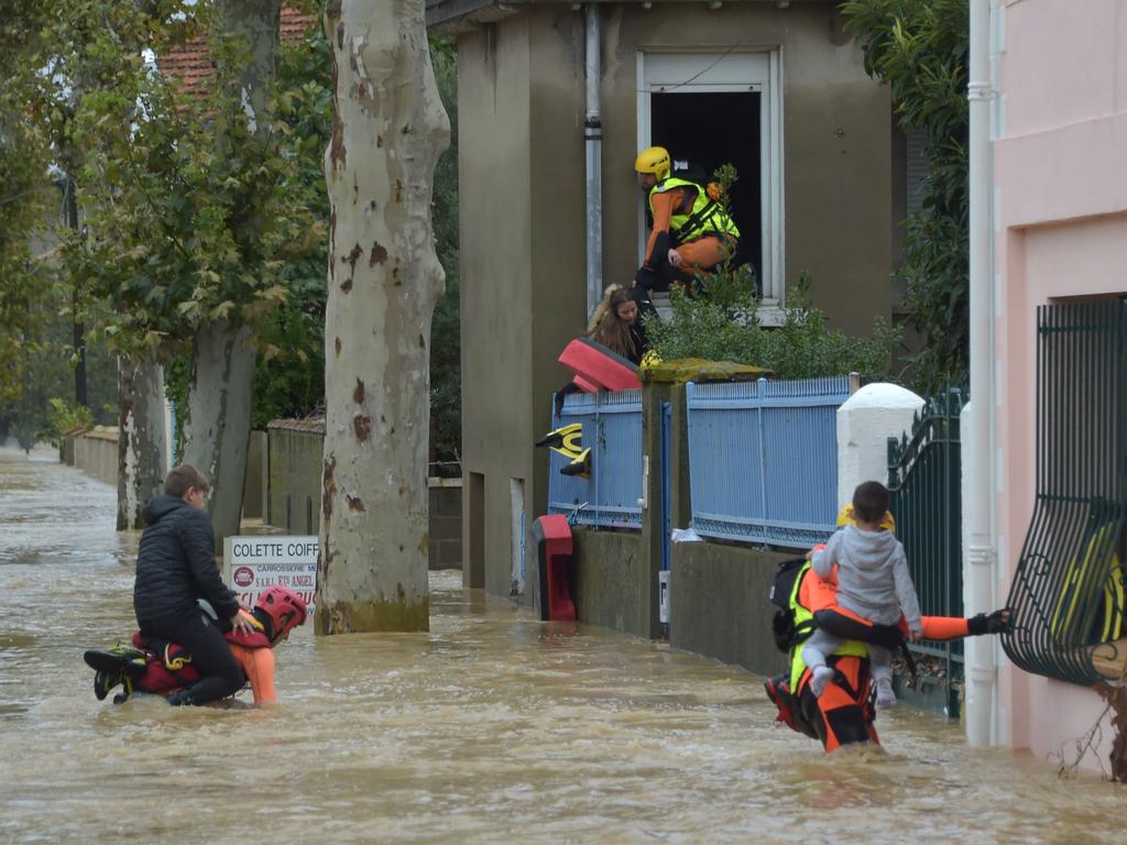 Firefighters help youngsters to evacuate in a flooded street in Trebes, near Carcassone, southern France. Picture: AFP