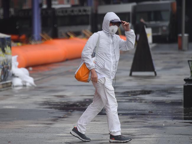 A person walks past flood barriers in lower Manhattan as Tropical Storm Isaias approaches New York City on August 4, 2020. - Isaias pounded the US eastern seaboard with driving rain and strong winds on August 4, leaving hundreds of thousands without power and prompting flood precautions in New York City. (Photo by Angela Weiss / AFP)