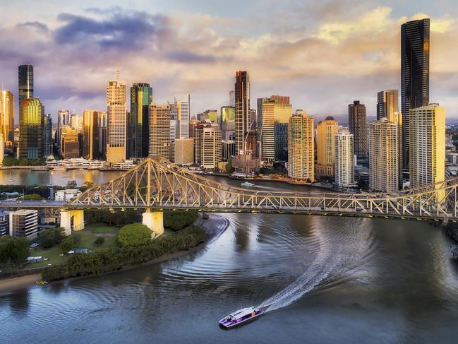 Developing Queensland - Close to Story Bridge across Brisbane River in front of Brisbane city CBD high-rise business and apartment towers with fast ferry on the water under the bridge.