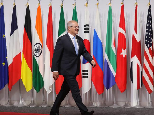 The Australian PM walks past G20 member flags as he is welcomed by Japan's Prime Minister Shinzo Abe to the G20 Summit in Osaka. Picture: AFP