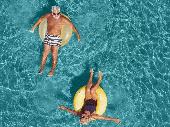 High angle view photo of a senior couple floating in the ocean while using swimming and floating devices; Retirement, travel generic retirees