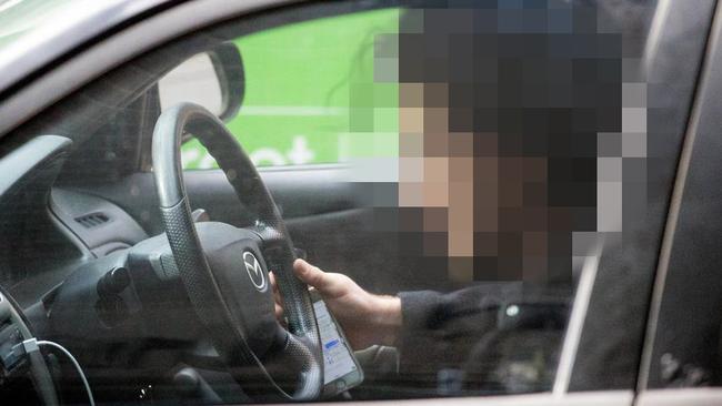 A driver grasps his phone while driving on Elizabeth St. Picture: Mark Stewart