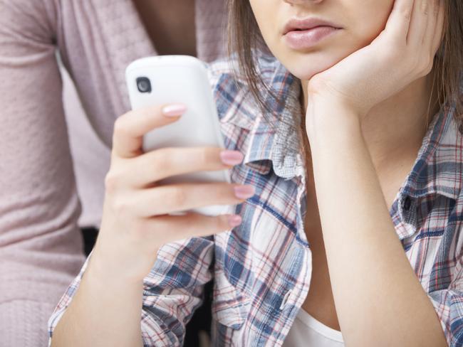 Mother Comforting Daughter Being Bullied By Text Message - Stock Image