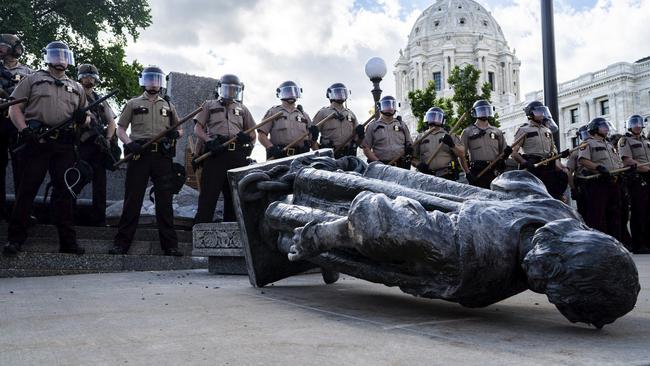 State troopers line up beside a fallen statue of Christopher Columbus in St Paul, Minnesota. Picture: AP