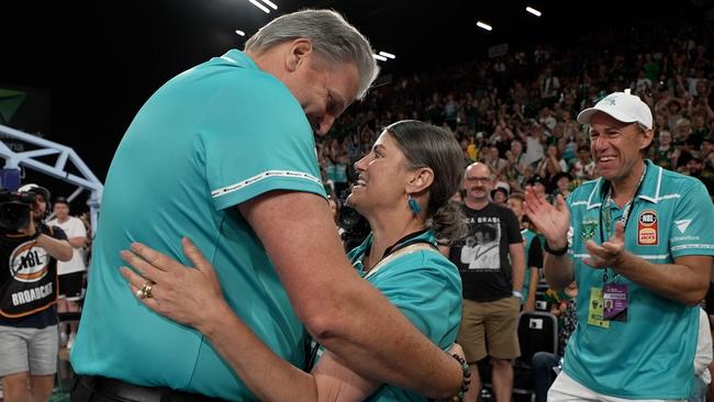 Tasmania JackJumpers head coach Scott Roth embraces Jo Harris in front of a packed crowd following the January 2023 teal match, as husband Scott Harris looks on. Picture: Supplied