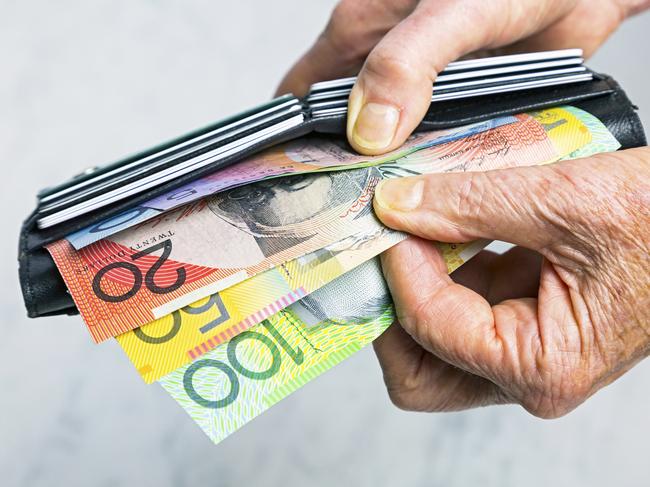 AUSTRALIAN CURRENCY/ DOLLARS/  PICTURE: istock Close-up, senior female hands taking Australian banknotes (cash, currency) from purse containing many credit cards.  Horizontal, studio, copy space.