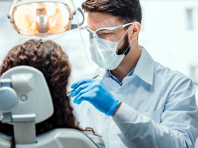 Dentist working in dental clinic with patient in the chair.