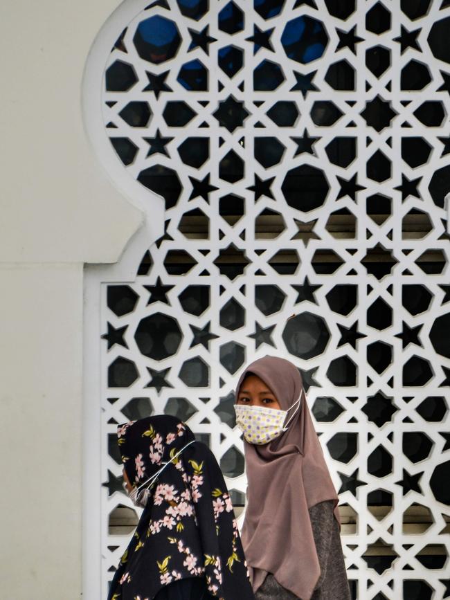 Women wearing face masks walk in front of the Baiturrahman Grand Mosque in Banda Aceh on March 6, 2020. Picture: AFP