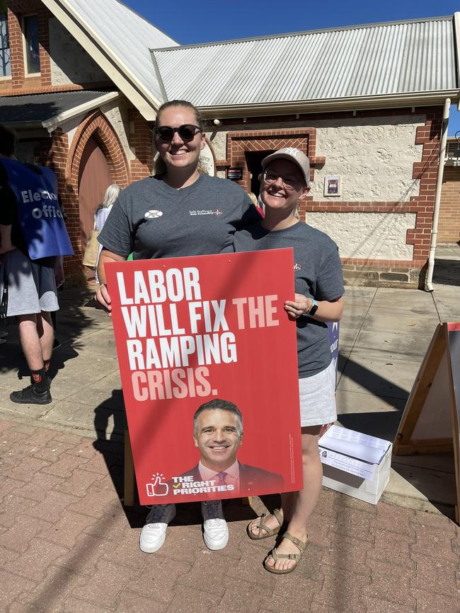 Paramedics Ashleigh “Ash the Ambo: Frier and Sian Wanstall with a Labor poster at a polling booth in the March 2022 election.