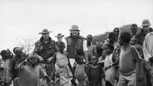 An Australian politician on a guided tour of Ufurow, 40km outside of Baidoa, poses here with local children. He is accompanied by Lieutenant Colonel David Hurley (left) who was the Commanding Officer of the 1st Battalion. Picture: Australian War Memorial