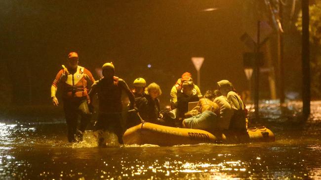 Carole Lloyd, grandson Dekota Davidson, Huana Cleaveland (with family cat), Tia Grace and Malia Cleveland are evacuated by Surf Rescue from their home in Mactier St, Narrabeen. Picture: Damian Shaw