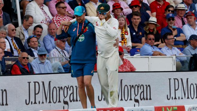 Australia's Nathan Lyon is helped off the field after picking up an injury. (Photo by Ian Kington / AFP)