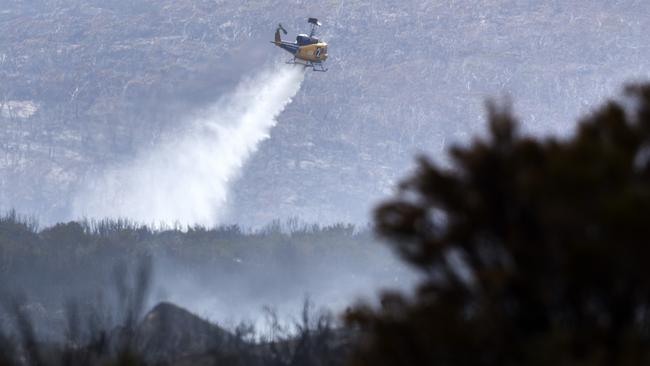 A helicopter drops water on spot fires near Lake Augusta Rd, Central Highlands. PICTURE CHRIS KIDD