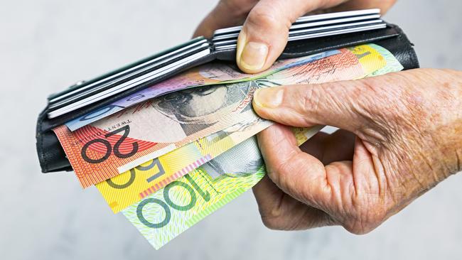 AUSTRALIAN CURRENCY/ DOLLARS/  PICTURE: istock Close-up, senior female hands taking Australian banknotes (cash, currency) from purse containing many credit cards.  Horizontal, studio, copy space.