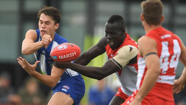 North Melbourne forward Curtis Taylor gets a handball away as he’s tackled by Aliir Aliir. Picture: Getty Images