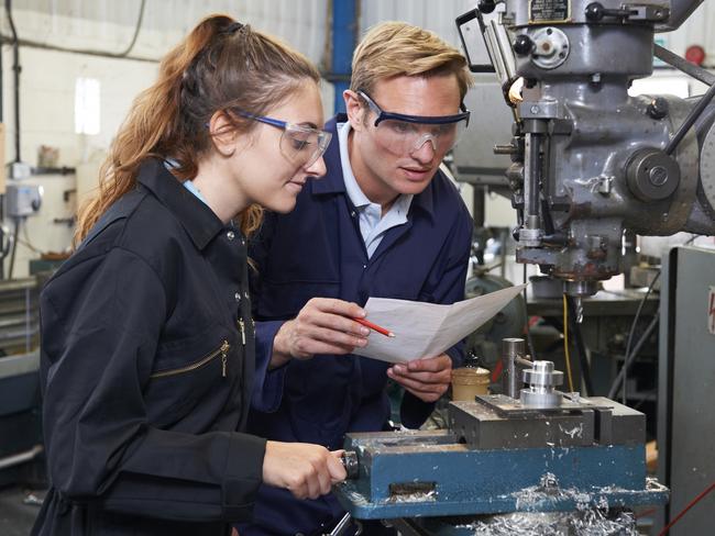 Engineer Showing Apprentice How to Use Drill In Factory