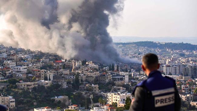 A journalist looks on as smoke billows from the site of several explosions during an Israeli raid in the occupied West Bank city of Jenin. Picture: AFP