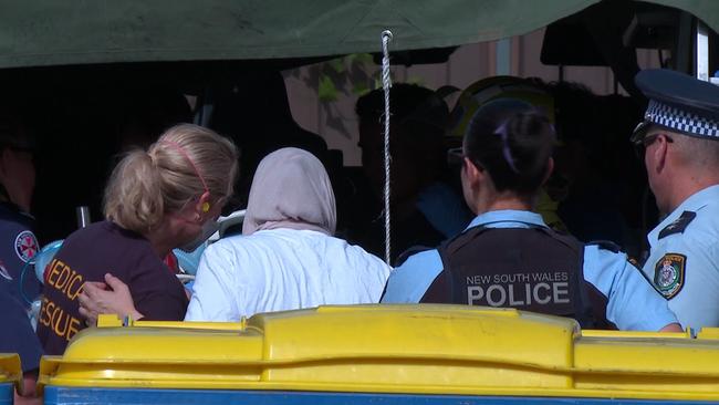 Shocked onlookers watch paramedics and police work on the woman. Picture: TNV