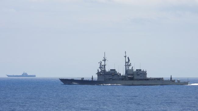 A Chinese aircraft carrier being monitored by a Taiwanese warship.