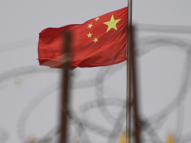 (FILES) This file photo taken on June 4, 2019 shows the Chinese flag behind razor wire at a housing compound in Yangisar, south of Kashgar, in China's western Xinjiang region. - The US will seize all imports of tomato and cotton products from China's Xinjiang region due to the use of forced labor, the Customs and Border protection agency announced on January 13, 2021. (Photo by GREG BAKER / AFP) / RESTRICTED TO EDITORIAL USE - MANDATORY CREDIT â AFP PHOTO / BADUNG POLICEâ - NO MARKETING - NO ADVERTISING CAMPAIGNS - DISTRIBUTED AS A SERVICE TO CLIENTS