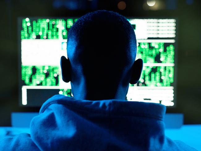 Rearview shot of a male hacker cracking a computer code in the dark