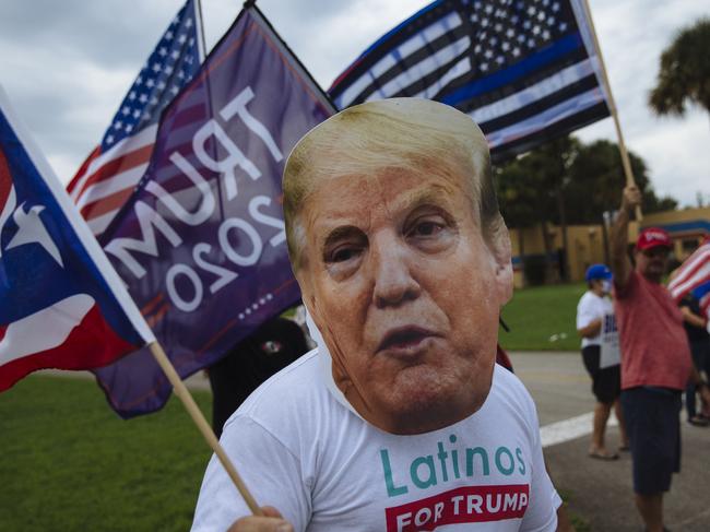 A man wearing a Trump mask with fellow Trump supporters outside an event where Joe Biden was campaigning in Floria. Picture: Angus Mordant/NewsCorp Australia