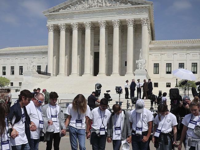 WASHINGTON, DC - MAY 03: Students and parents from the Wickenberg Christian Academy, in Wickenberg, Arizona, pray in front of the U.S. Supreme Court Building on May 03, 2022 in Washington, DC. In a leaked initial draft majority opinion obtained by Politico and authenticated by Chief Justice John Roberts, Supreme Court Justice Samuel Alito wrote that the cases Roe v. Wade and Planned Parenthood of Southeastern Pennsylvania v. Casey should be overturned, which would end federal protection of abortion rights across the country.   Win McNamee/Getty Images/AFP == FOR NEWSPAPERS, INTERNET, TELCOS & TELEVISION USE ONLY ==